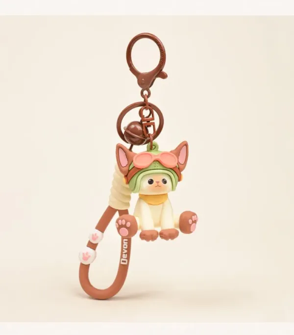 Cute cat keychain with Devon label, wearing green strawberry hat, brown bell and paw accessories