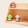 Three cute panda figurines with colorful hats on wooden display shelves, pink one has keychain