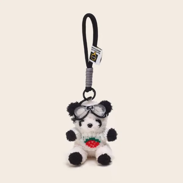 Plush panda keychain wearing goggles and strawberry sweater with black loop strap