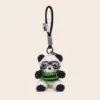 Plush panda keychain wearing green striped sweater and aviator goggles with black loop strap