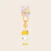 Cute cat keychain with yellow fox hood, white body, and orange clasp on retail card