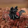 Black Toothless dragon toy figure with red tail fin on rocky surface, OFF-ON switch visible