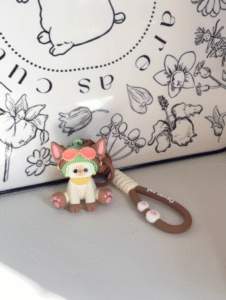 Cute Devon Cat keychain figure wearing green frog hat with goggles and pink paw pads