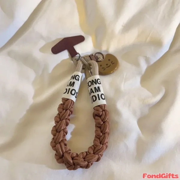 Braided brown leather phone strap with Kong Sam Studio text labels and cat charm
