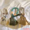 Three triangular canvas coin pouches with rope straps in beige, green, and tan colors