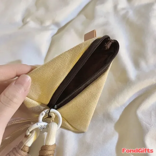 Hand holding open yellow canvas coin pouch with brown lining and zipper