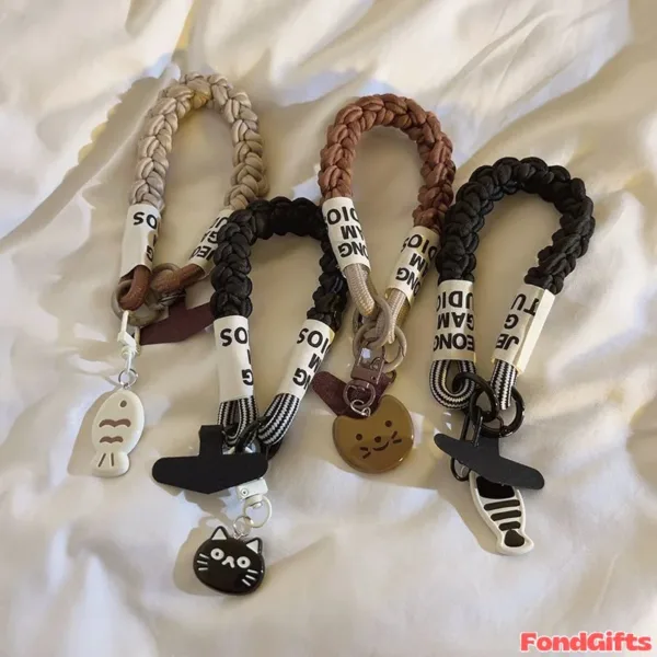 Three braided leather keychains with cute cat and fish charms on fabric background