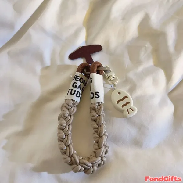Braided beige phone strap with fish charm and JEONG GAME STUDIOS fabric tag