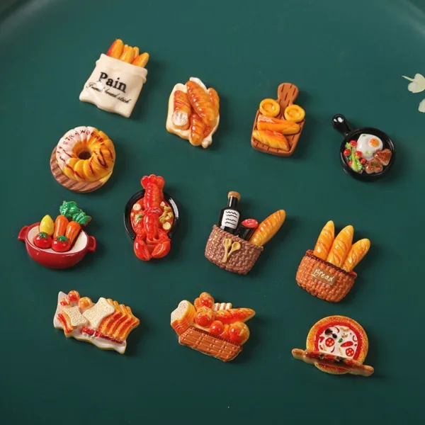 Colorful miniature food fridge magnets featuring bread, pastries, lobster, pizza, and breakfast items on green surface