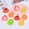 Colorful resin fruit slice charms including watermelon, orange, lemon, kiwi, and strawberry on white surface