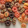 Colorful artisan breads shaped like flowers, leaves, and braided rings in orange, green, and brown hues