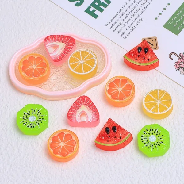 Colorful resin fruit slice charms including watermelon, orange, lemon, and kiwi on pink tray