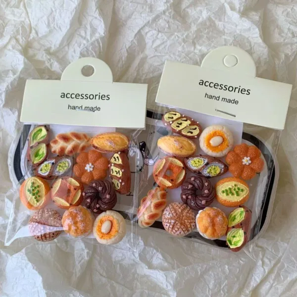 Two packages of handmade miniature bread and pastry accessories on white paper