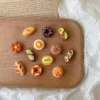 Miniature clay pastries and bread arranged on wooden tray with vintage book