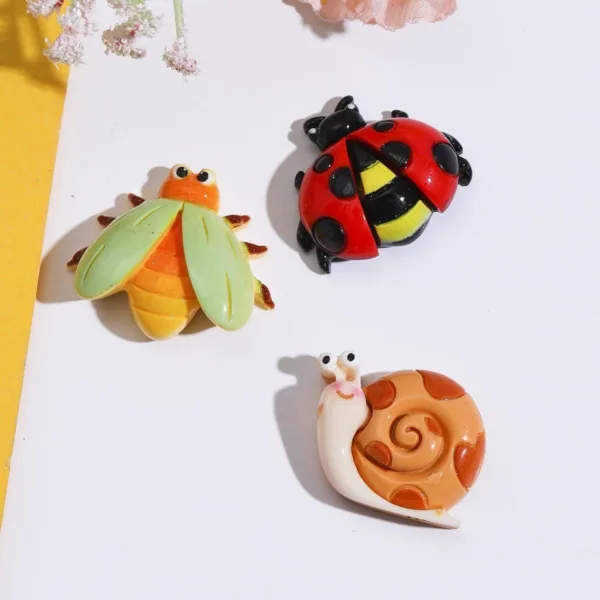 Three colorful ceramic garden creature figurines - bee, ladybug, and snail on white surface