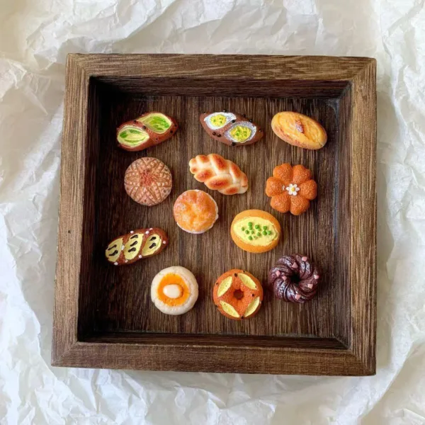 Miniature clay pastries and breads displayed on a wooden tray
