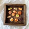 Miniature clay bread and pastry sculptures displayed on a wooden tray