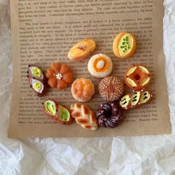 Miniature clay pastries and bread arranged on vintage entomology book page