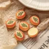Miniature papaya-shaped cookies with green seed details on crinkled brown paper and newspaper