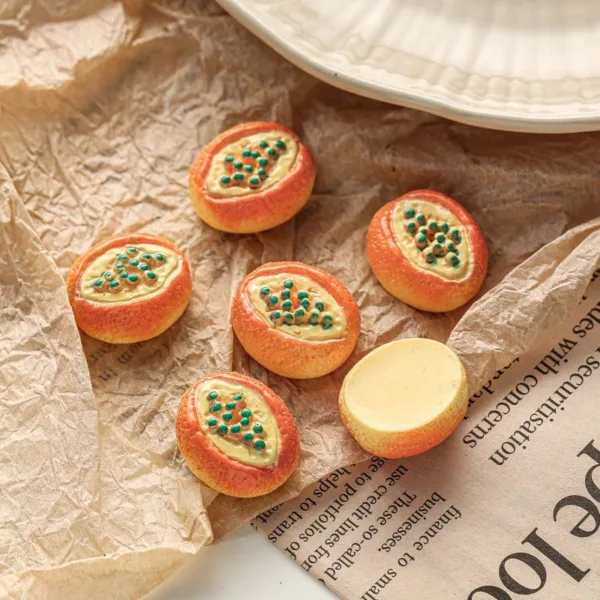 Miniature papaya-shaped cookies with green seed details on crinkled brown paper and newspaper