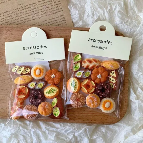 Two clear bags of handmade miniature bread and pastry accessories on wooden surface