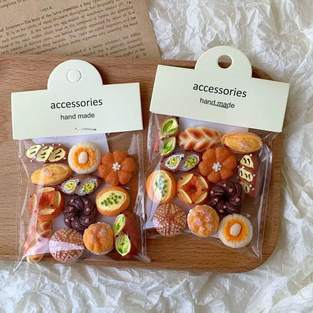 Two clear bags of handmade miniature bread and pastry accessories on wooden surface