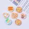 Miniature resin food charms featuring dumplings, fried eggs, pizza, cookies, and churros on tiny plates