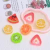 Colorful resin fruit slice charms including watermelon, kiwi, orange, lemon, and strawberry on decorative tray
