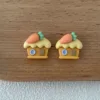 Cute carrot house earrings in orange and yellow on wooden surface
