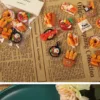 Miniature resin food charms featuring bread baskets, breakfast skillets, and pastries on newspaper background