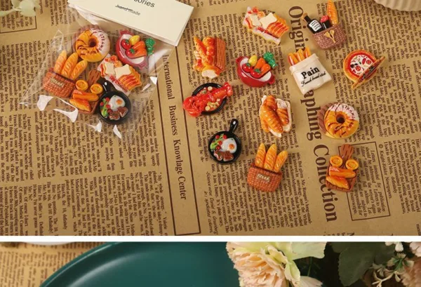 Miniature resin food charms featuring bread baskets, breakfast skillets, and pastries on newspaper background