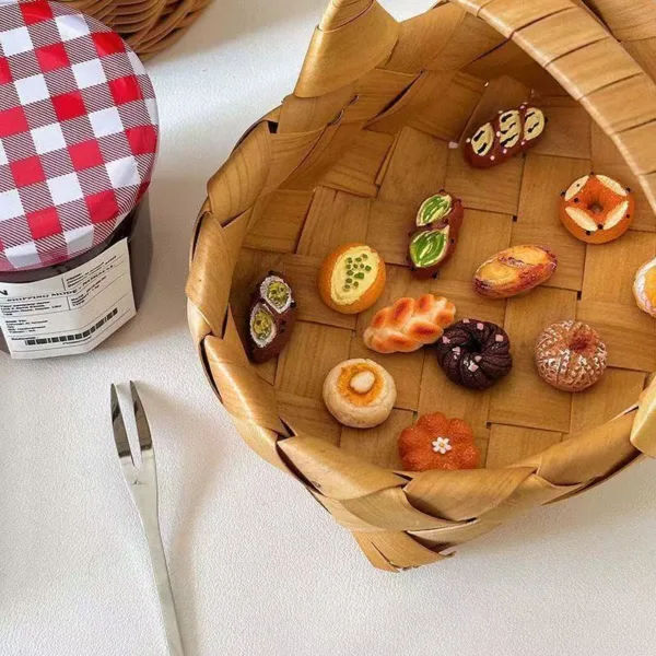 Miniature pastries and baked goods displayed in a woven wooden basket with tongs