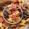 Colorful assorted miniature cookies in a white bowl with autumn-themed shapes and designs