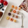 Miniature polymer clay pastries and breads next to blueberries and cherry tomatoes