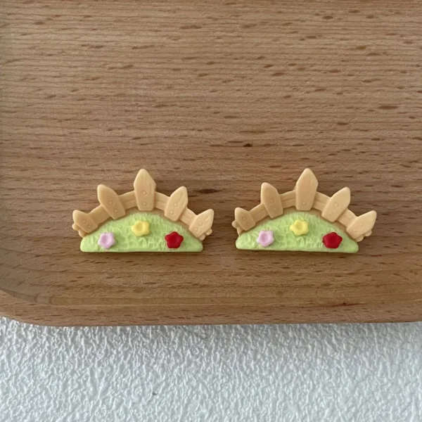 Handmade polymer clay earrings shaped like garden fences with green grass and colorful flowers