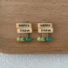 Two miniature Happy Farm wooden sign charms with grass details on wooden tray