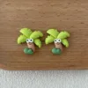 Cute polymer clay palm tree stud earrings with googly eyes on wooden surface