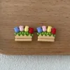 Colorful tulip earrings in wooden planter boxes on oak surface
