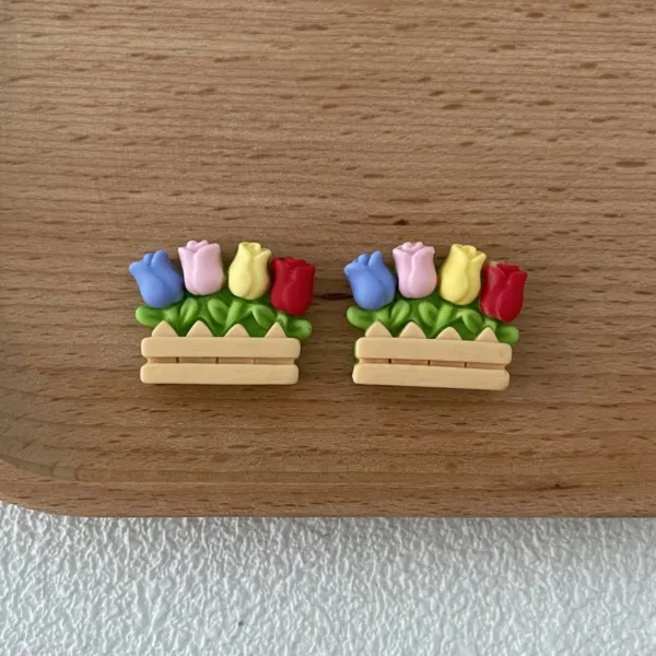 Colorful tulip earrings in wooden planter boxes on oak surface