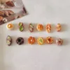 Miniature polymer clay bakery items including eclairs, donuts, and pastries arranged in two rows