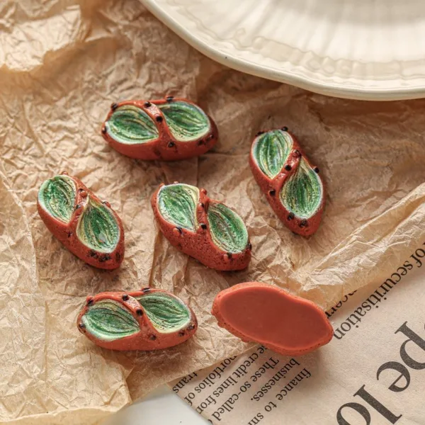 Miniature prickly pear cactus fruit resin charms on crinkled paper and newspaper