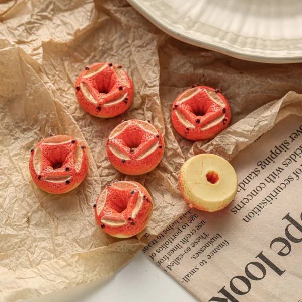 Miniature strawberry donuts with cream filling on crinkled brown paper and newspaper